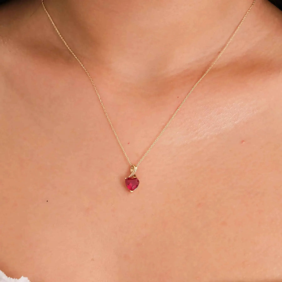 Primo piano della collana con ciondolo cuore in oro giallo 14kt con rubino creato in laboratorio indossata al collo