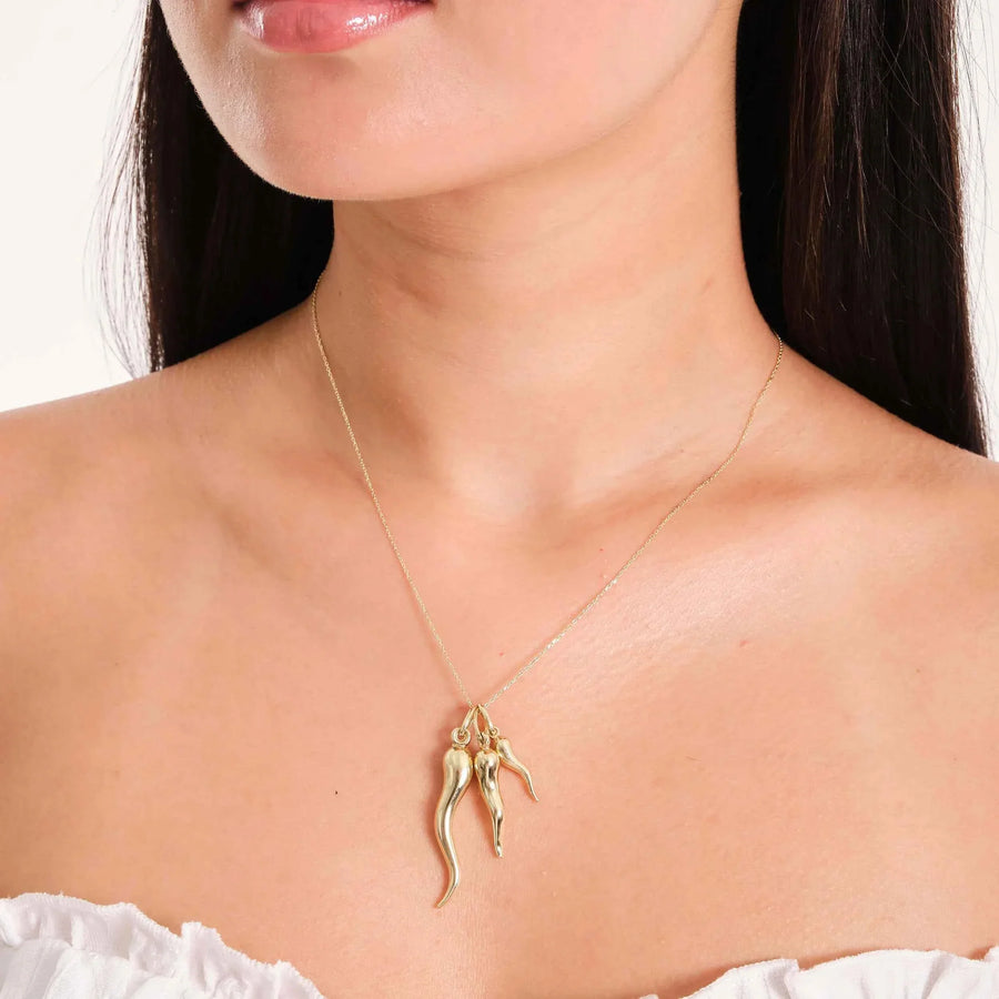 Vue de côté du collier pendentif corne italienne (cornicello) en or jaune 14 carats porté au cou