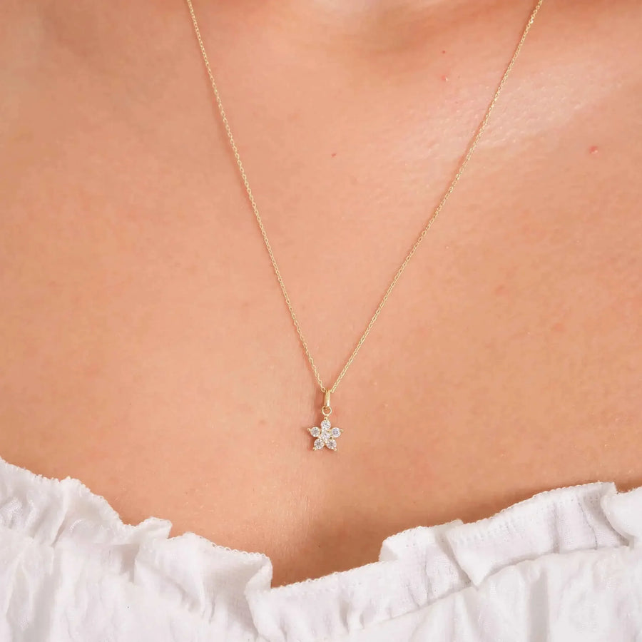 Primo piano della collana con ciondolo fiore a stella con zirconi in oro giallo 14kt indossata al collo