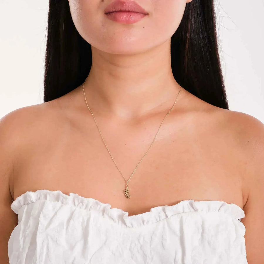 Collier pendentif branche d'olivier en or jaune 14 carats porté par un mannequin en haut bustier blanc
