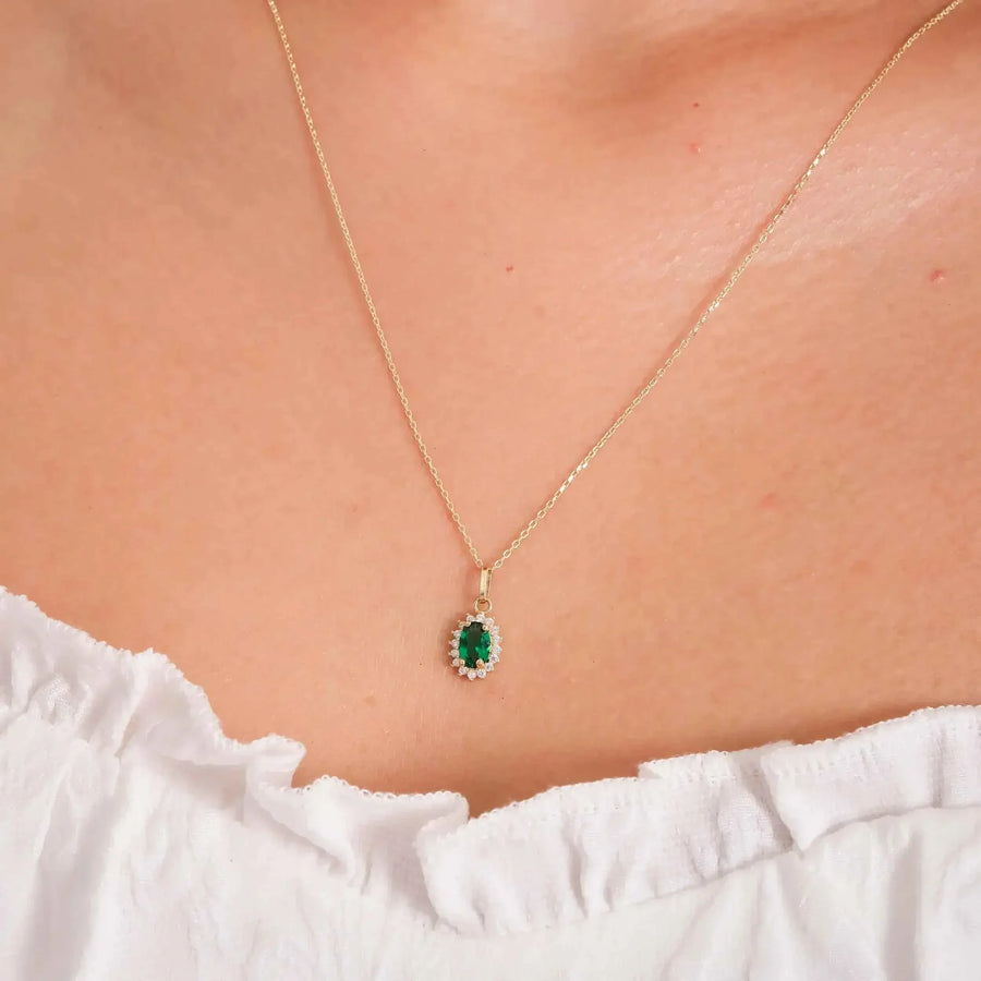 Primo piano della collana con ciondolo halo in oro giallo 14kt con smeraldo creato in laboratorio indossata al collo