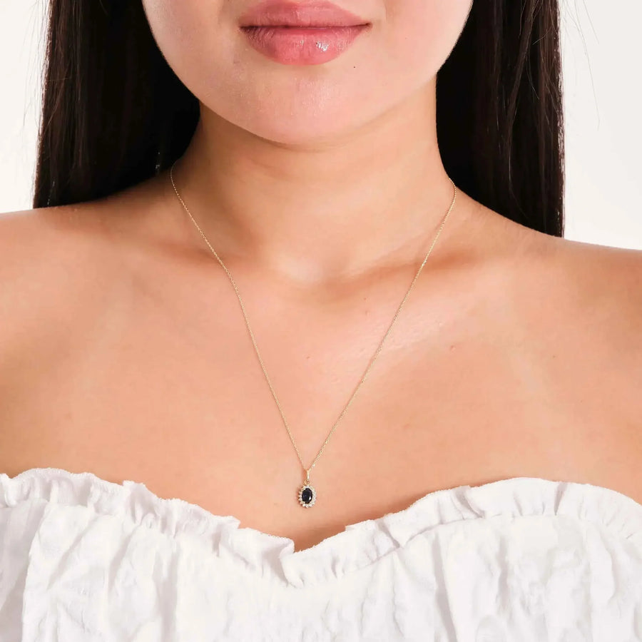 Collar con colgante halo de zafiro de laboratorio en oro amarillo de 14 quilates llevado por la modelo con top blanco de hombros descubiertos