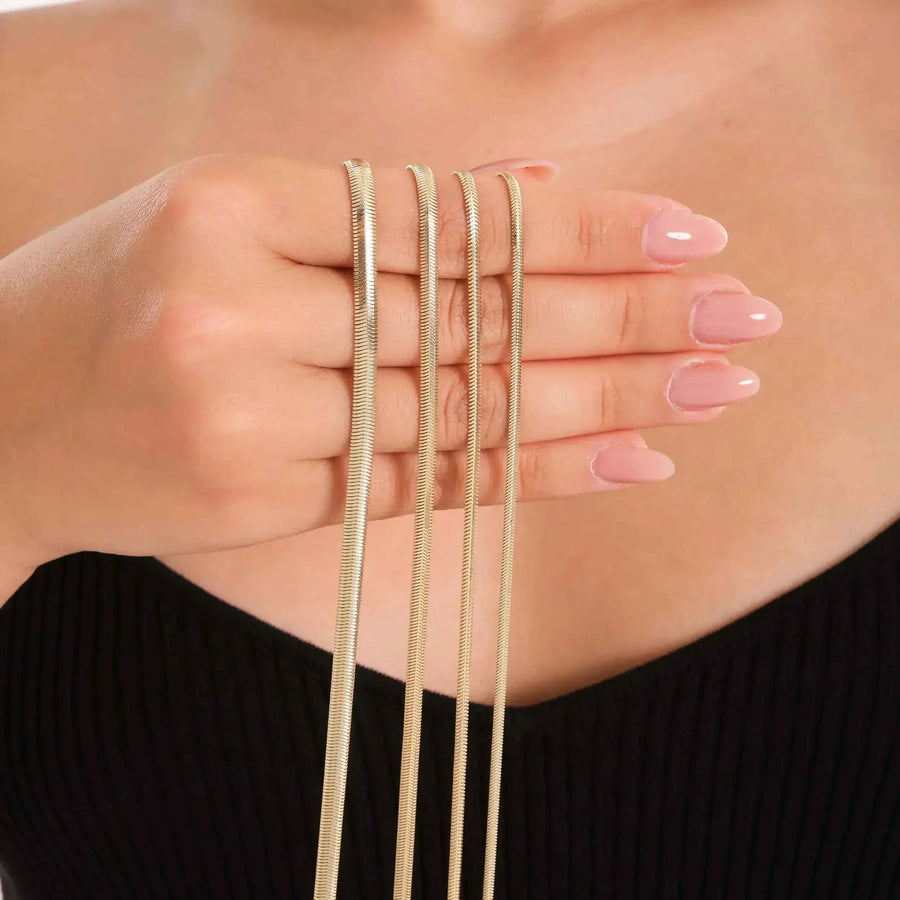 14K yellow gold flat herringbone chain necklaces in several widths draped over hand