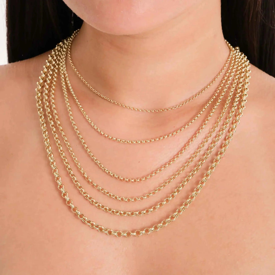 Primer plano de cadenas rolo en oro amarillo de 14 quilates superpuestas en el cuello