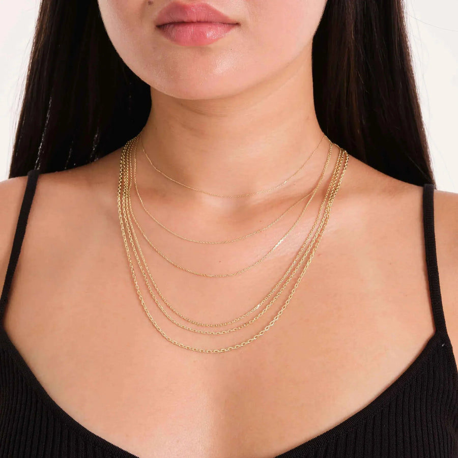 Plusieurs chaînes maille forçat taille diamant en or jaune 14 carats superposées, portées par un mannequin