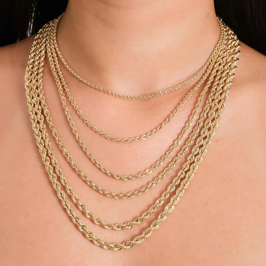 Close-up of 14K yellow gold rope chain necklaces layered on neck