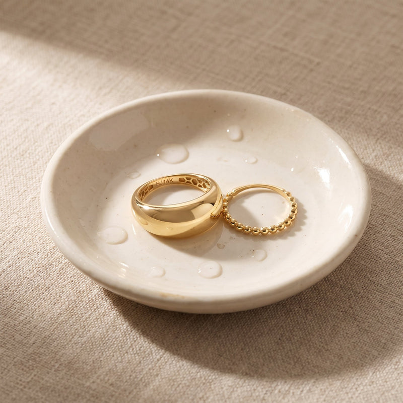 Bague dôme et bague bulles en or 14 carats dans une petite coupelle en céramique ivoire