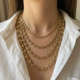 Collane a maglia marina in oro giallo 14kt indossate a strati dalla modella con camicia bianca