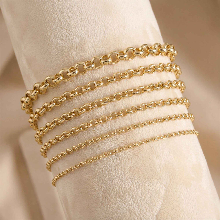 Bracelets maille rolo en or jaune 14 carats de largeurs graduées enroulés autour d'un rouleau de présentation crème