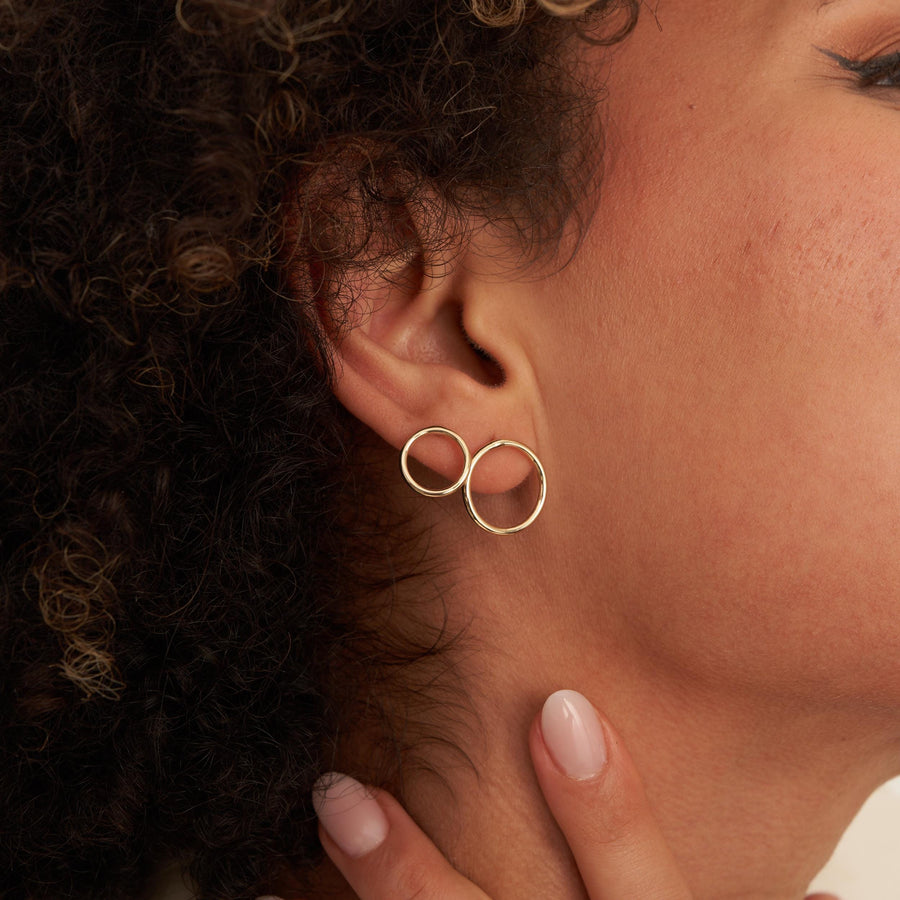 Oreille avec deux puces d'oreilles créole cercle en or jaune 14 carats, la main au cou, vue de côté