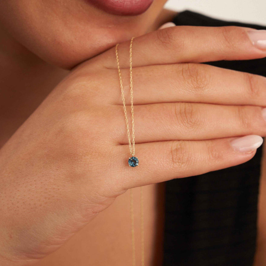London-Blue-Topas-Solitärhalskette aus 585er Gelbgold über die Hand des Models am Kinn gelegt