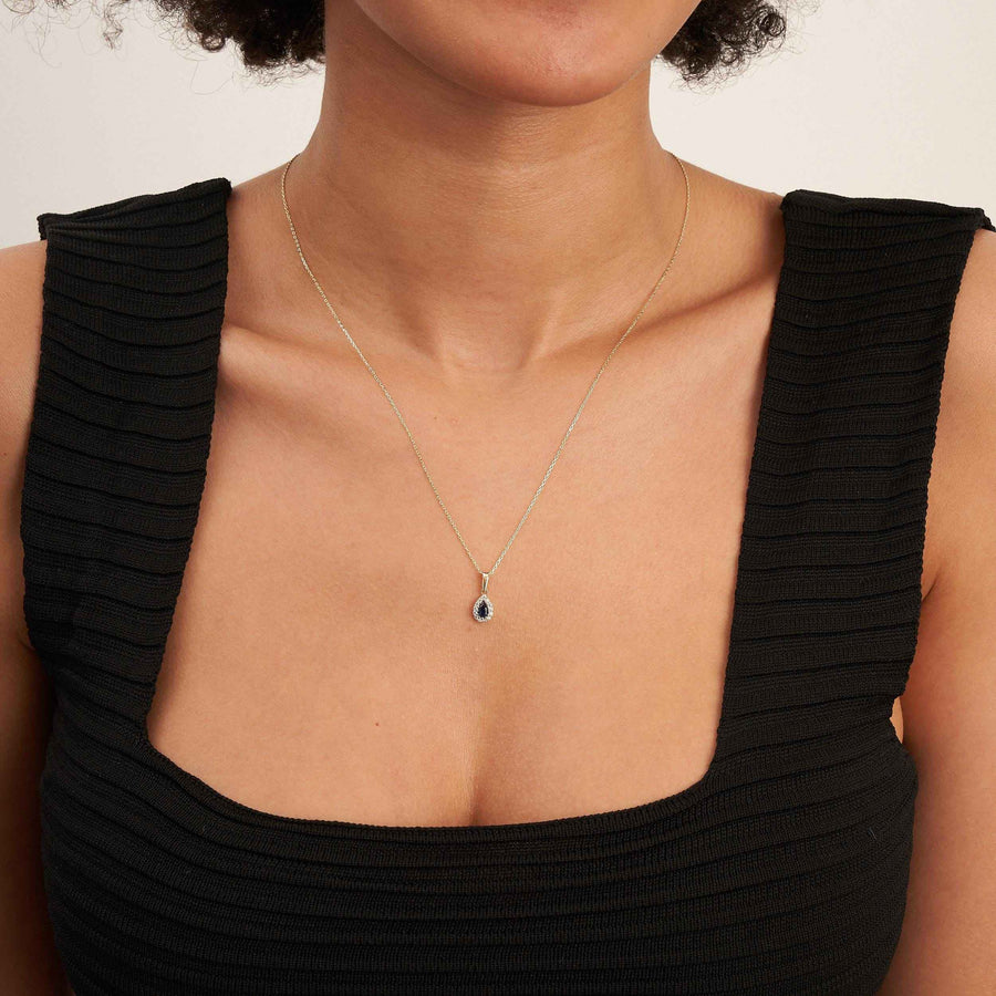 Collier pendentif halo saphir poire de synthèse en or jaune 14 carats porté par un mannequin en haut noir