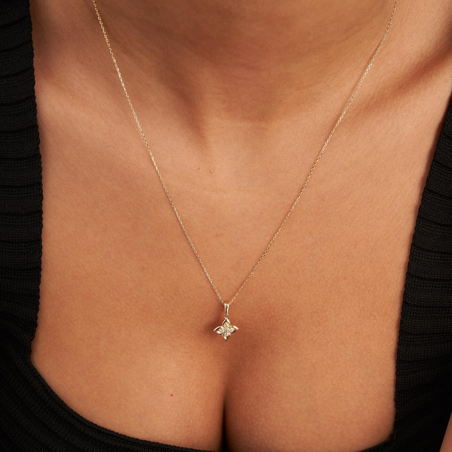 Gros plan sur le pendentif fleur trèfle en or jaune 14 carats posé sous la clavicule