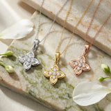Colliers fleur de trèfle en or blanc, jaune et rose 14 carats sur du marbre avec des fleurs blanches