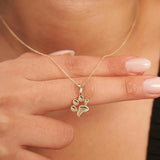 Doigts tenant le pendentif empreinte de patte en or jaune 14 carats au niveau du décolleté