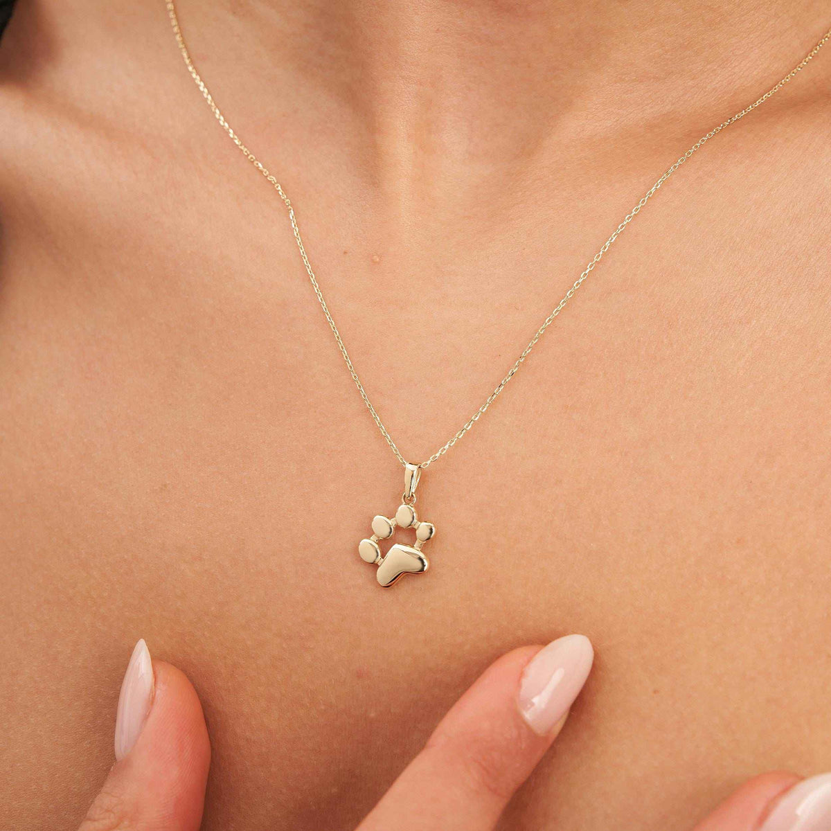 Collier empreinte de patte en or jaune 14 carats porté au cou, bout des doigts en dessous