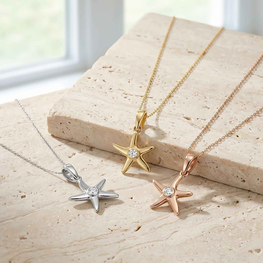 Colliers pendentif étoile de mer en or jaune, blanc et rose 14 carats posés sur un bloc de travertin
