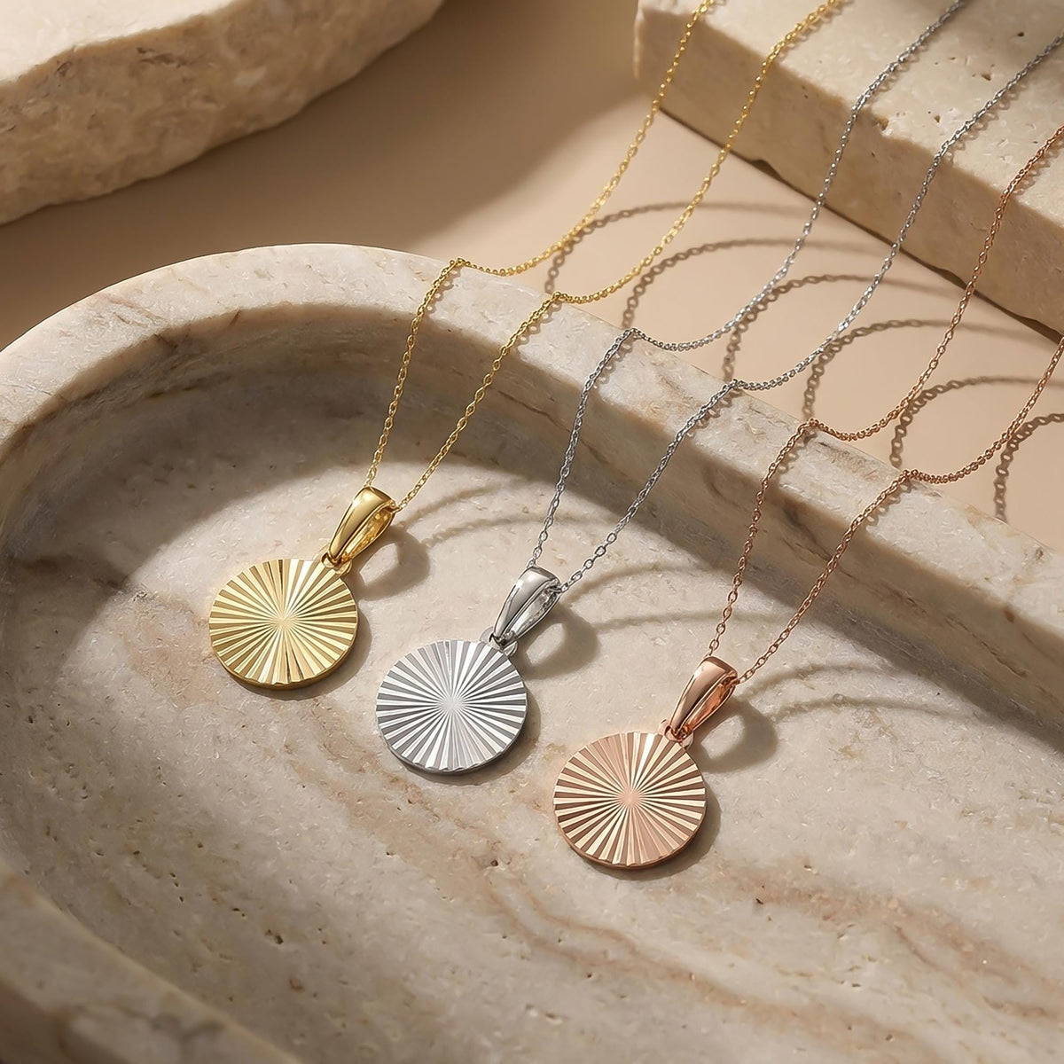 Collares de disco de sol radiante en oro amarillo, blanco y rosa de 14 quilates sobre travertino