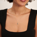 Modella sorridente con top nero indossa una collana in oro giallo 14kt con smeraldo taglio pera creato in laboratorio