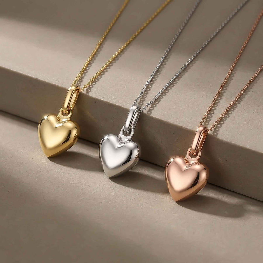 Pendentifs cœur bombé 3D en or jaune, blanc et rose 14 carats alignés sur un rebord en pierre