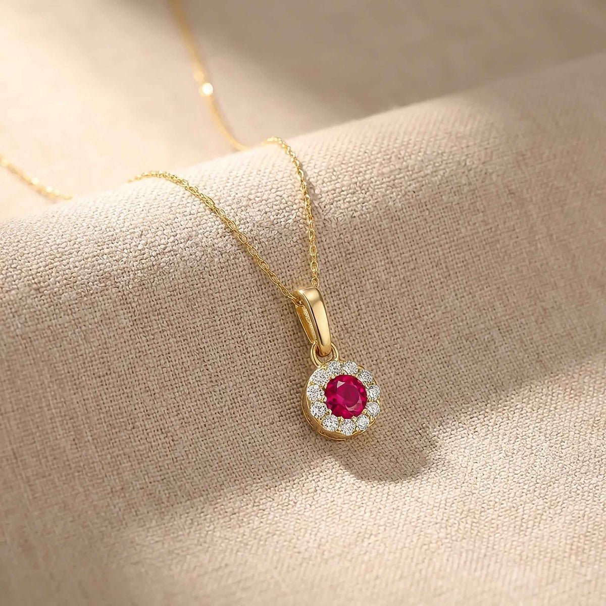 Pendentif halo rubis rond de synthèse en or jaune 14 carats drapé sur du lin, gros plan