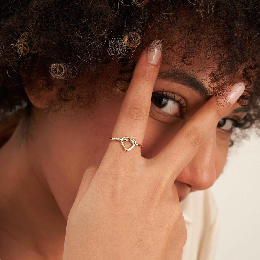 Modella che sbircia tra le dita indossa un anello aperto con cuore infinito in oro 14kt