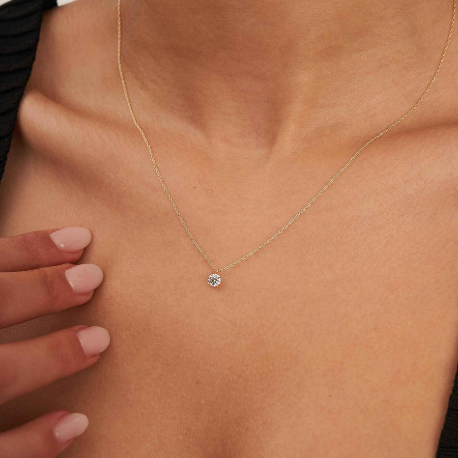 Gros plan du collier solitaire topaze blanche en or jaune 14 carats posé sur la clavicule