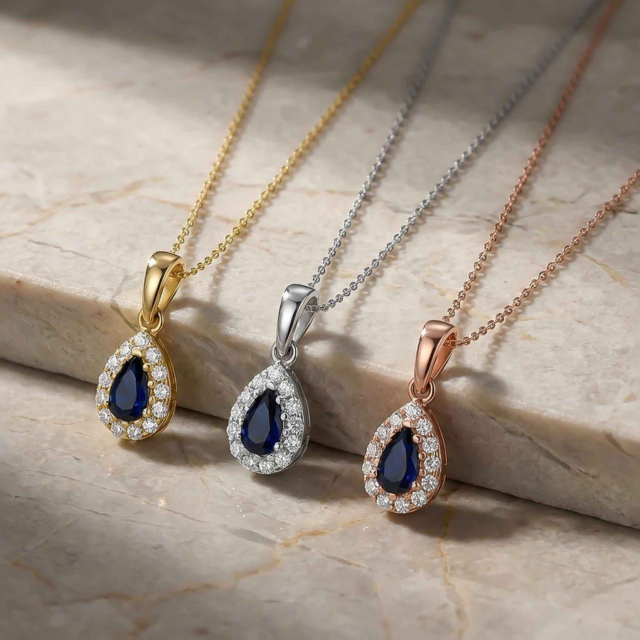 Colliers pendentifs halo saphir poire de synthèse en or jaune, blanc et rose 14 carats côte à côte sur du marbre