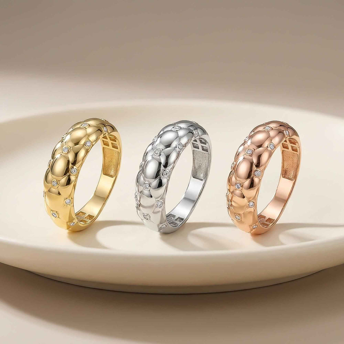 Bubble-Kuppelringe mit Zirkonia aus 585er Gelbgold, Weißgold und Roségold auf einem weißen Teller