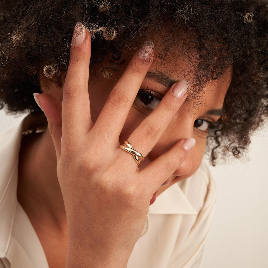 Modelo con la mano sobre el rostro y un anillo cruzado en oro amarillo de 14 quilates