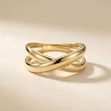 Anillo cruzado en oro amarillo de 14 quilates sobre fondo beige