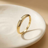 Anillo acanalado en oro amarillo de 14 quilates apoyado en un plato de cerámica blanco