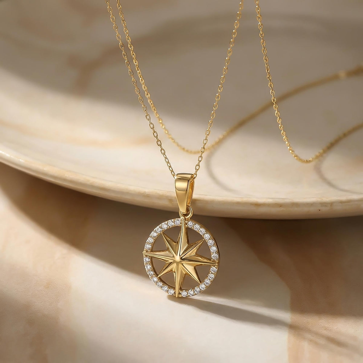 14K yellow gold compass star necklace on a marble plate