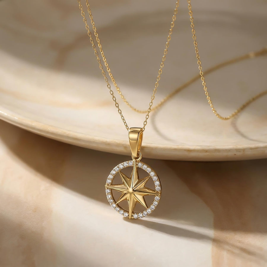 14K yellow gold compass star necklace on a marble plate