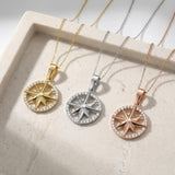 14K yellow, white and rose gold compass star necklaces on a stone tray