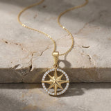 Close-up of 14K yellow gold compass star pendant on textured stone