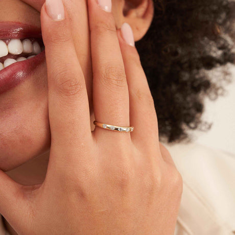 Primer plano del anillo con circonitas en oro amarillo de 14 quilates en el dedo, junto a la sonrisa de la modelo