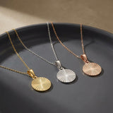Collares de disco de sol radiante en oro amarillo, blanco y rosa de 14 quilates en un plato oscuro
