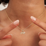 Fingers holding the 14K yellow gold infinity pendant at the neckline