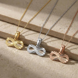 14K yellow, white and rose gold infinity necklaces on a stone ledge