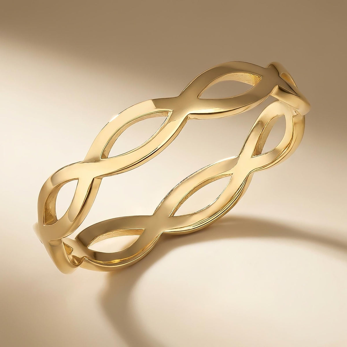 Bague infini ajourée en or jaune 14 carats sur fond beige