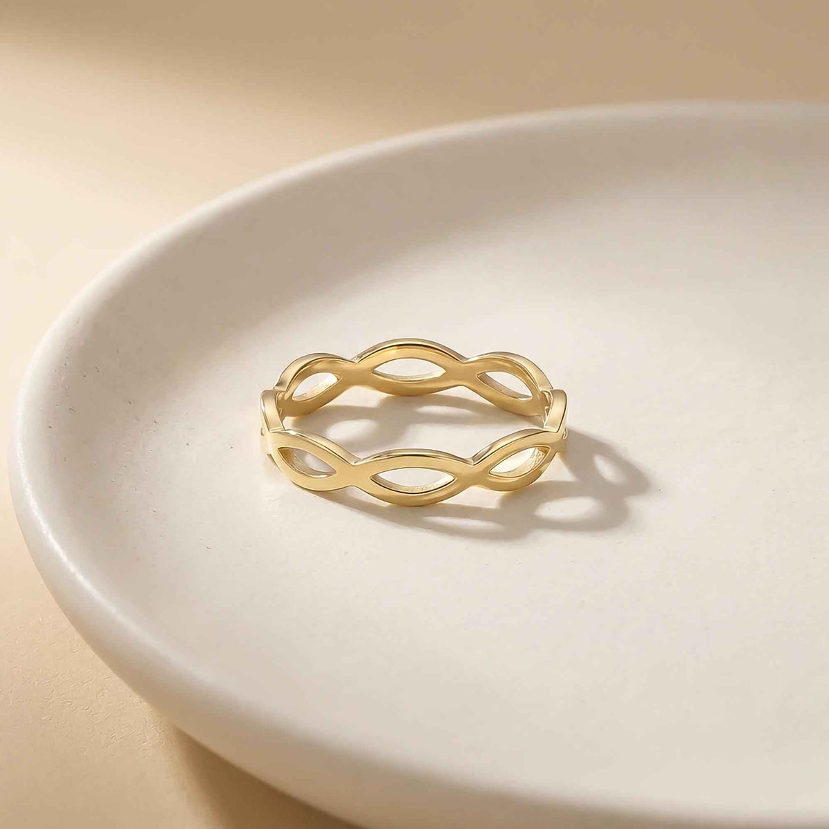 Bague infini ajourée en or jaune 14 carats sur une assiette blanche