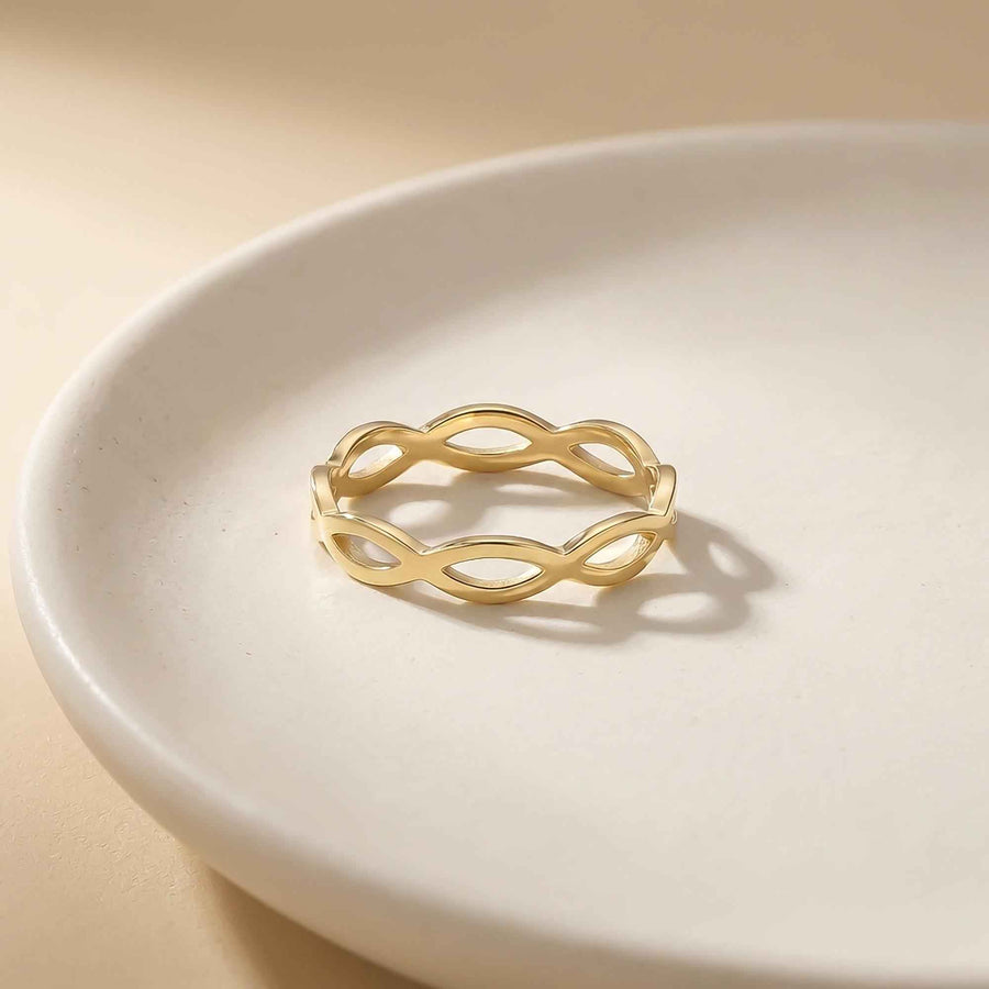 Bague infini ajourée en or jaune 14 carats sur une assiette blanche