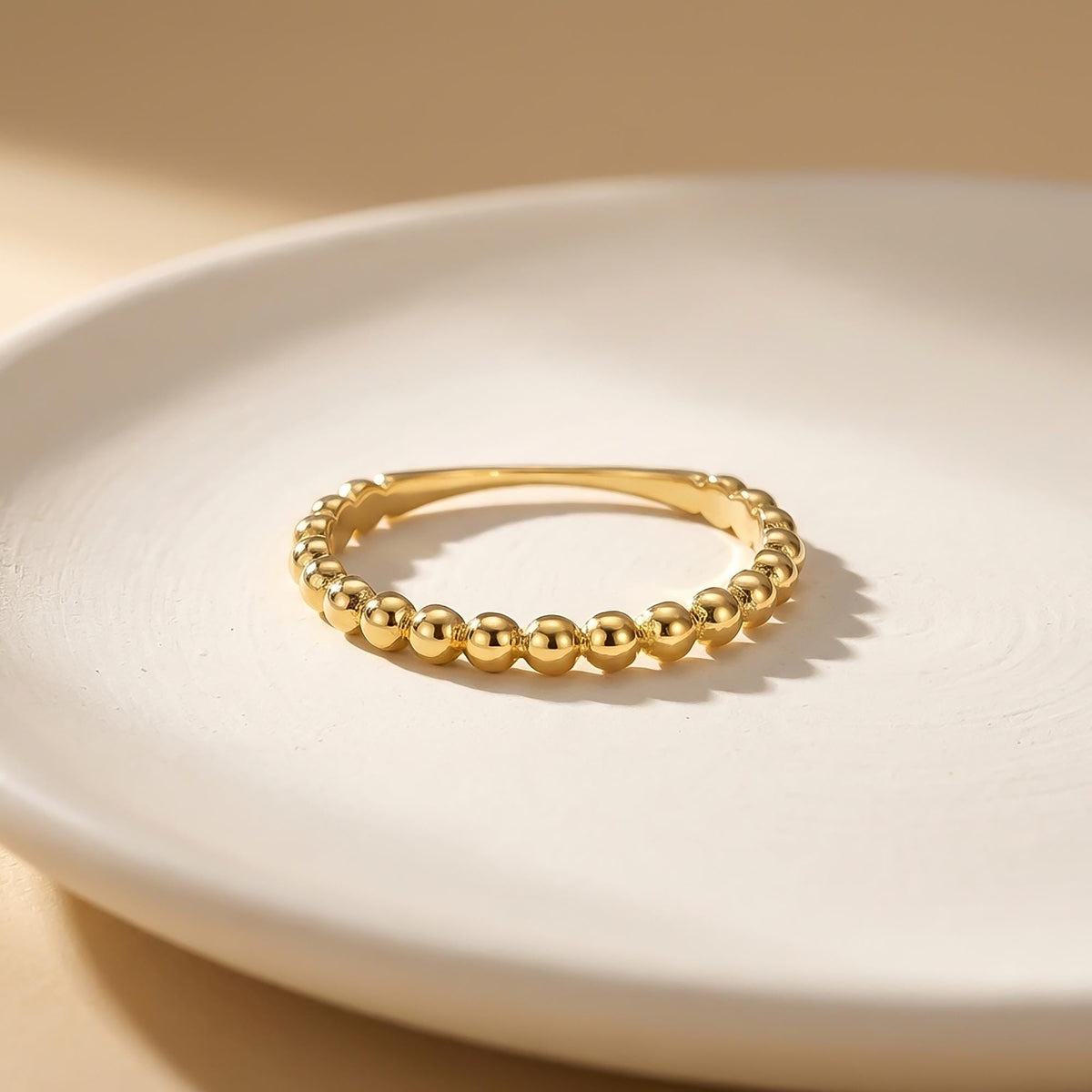 Anillo burbuja en oro amarillo de 14 quilates sobre un plato blanco