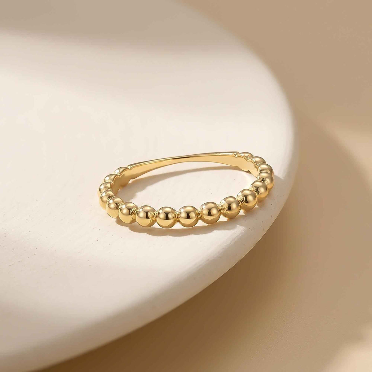 Anillo burbuja en oro amarillo de 14 quilates sobre un plato blanco
