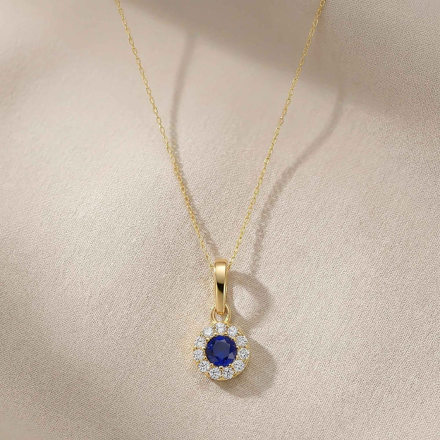 Collier halo saphir rond de synthèse en or jaune 14 carats sur fond crème