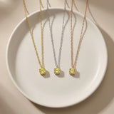 Collares solitarios de citrino en oro amarillo, blanco y rosa de 14 quilates sobre un plato blanco
