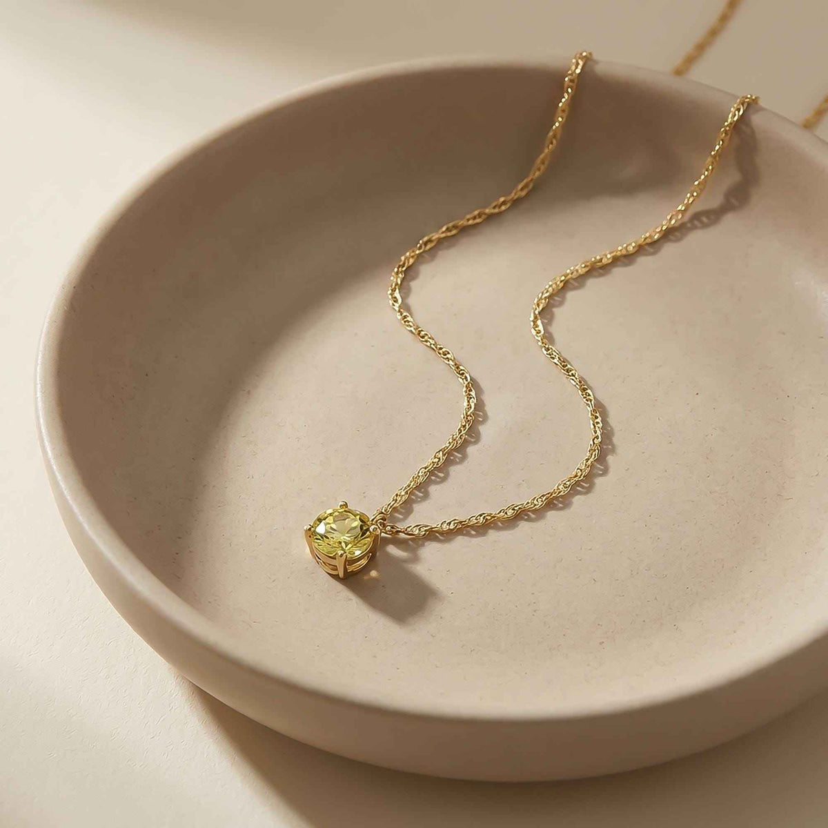 Collar solitario de citrino en oro amarillo de 14 quilates enrollado en un plato de cerámica