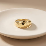 Kuppelring mit Wirbelmuster aus 585er Gelbgold auf weißem Teller, Gravur an der Innenseite sichtbar