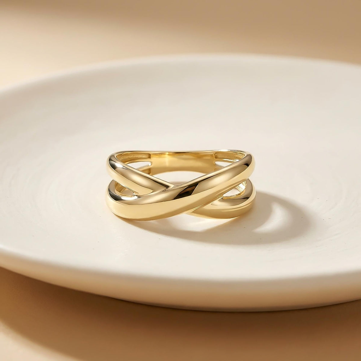 Anillo cruzado en oro amarillo de 14 quilates sobre un plato blanco